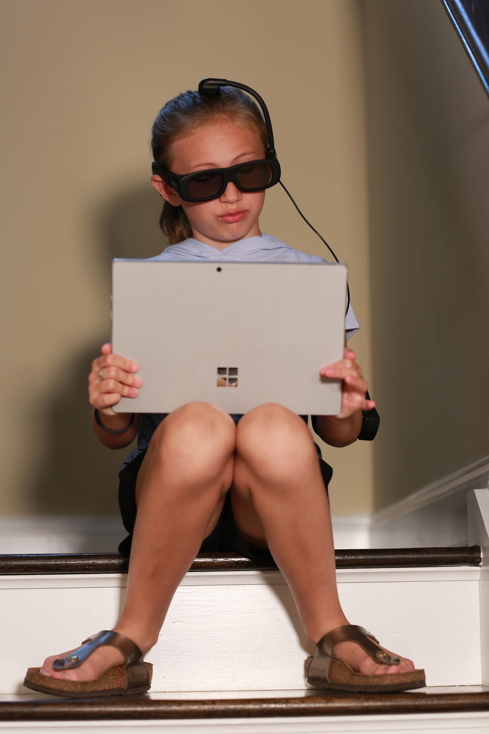 A girl wearing Narbis smart glasses while reading on a tablet